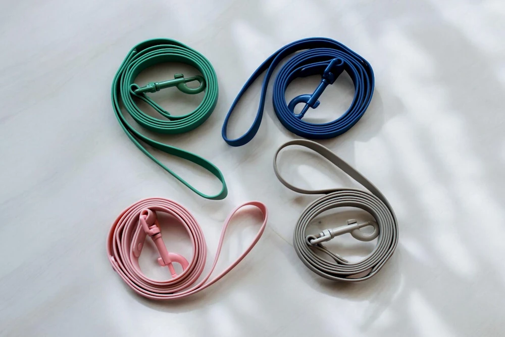 Four silicon dog leads of various colours, nicely arranged on a stone benchtop.