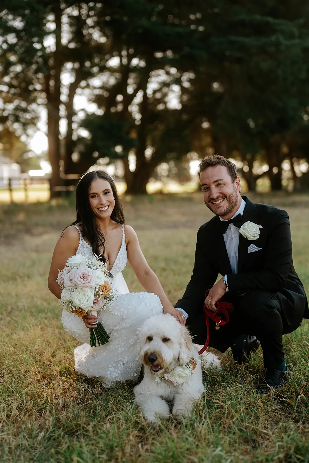 A very happy groodle poses with their parents - the bride and groom - on their wedding day.